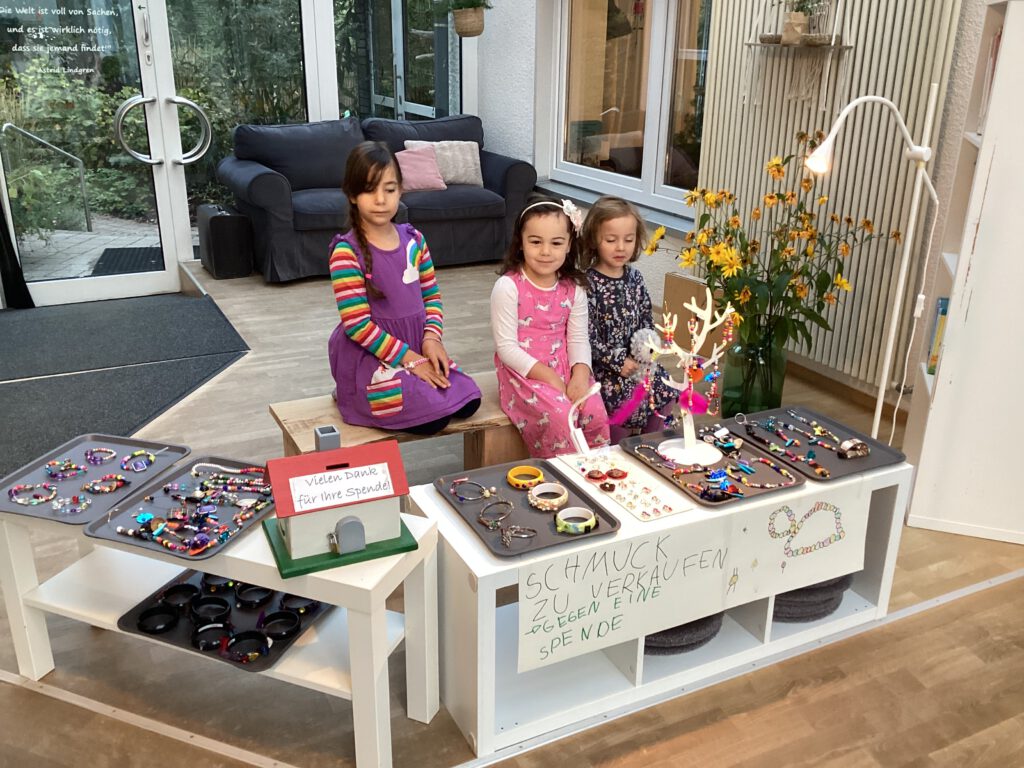 Alessia, Juna und Leonie verkaufen den Schmuck am Schmuckstand.